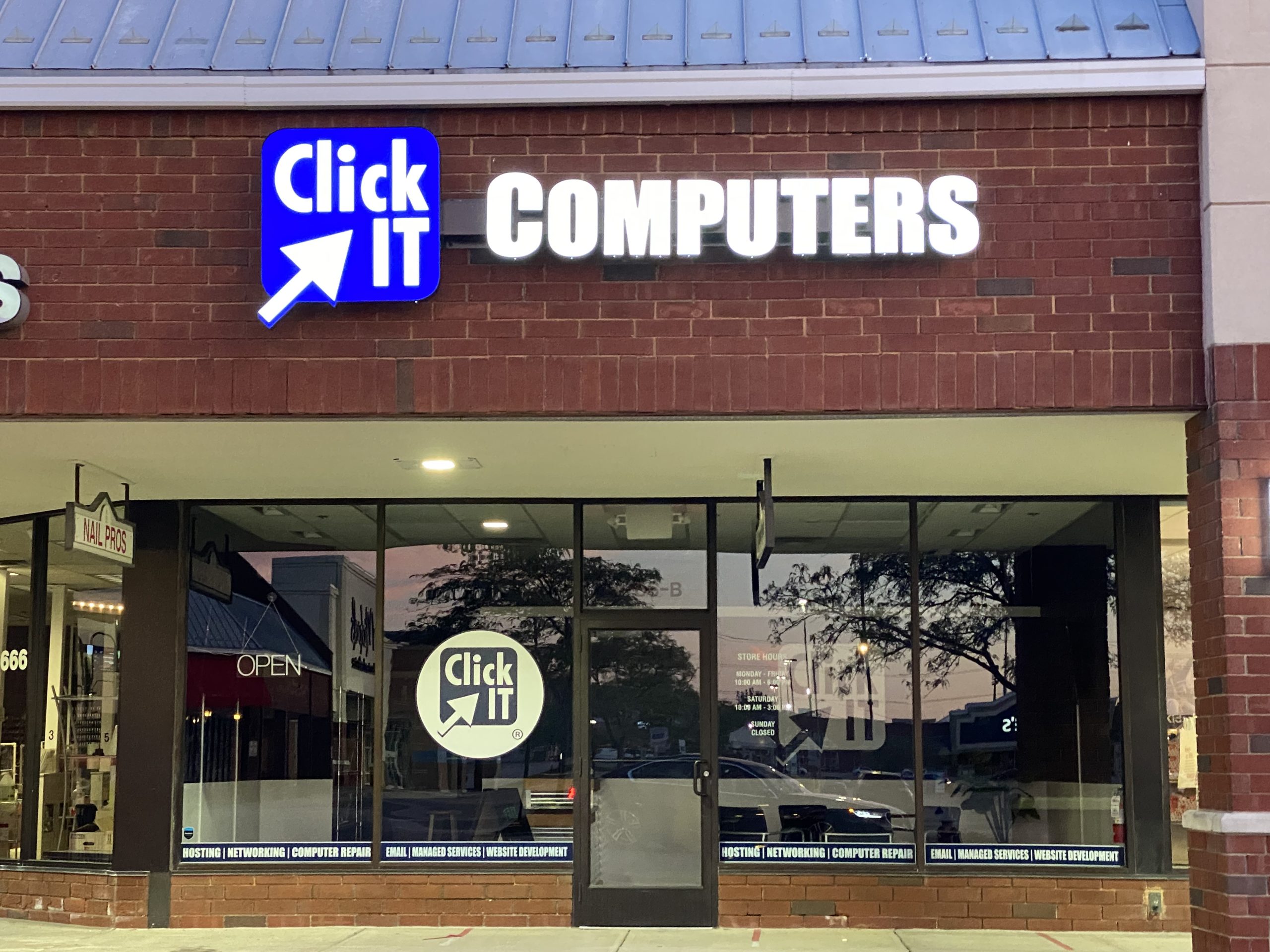 Illuminated Click IT Computers storefront sign closeup